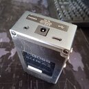Stříbrný kovový efekt pedál značky BOSS. Na horní hraně jsou konektory s popisky PHONES, DC IN USE BOSS PSA ADAPTOR ONLY 8V (spolu s ikonou polarity)…