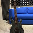Elektrická kytara s tmavě zeleným průsvitným povrchem s viditnou strukturou dřeva. Na hlavě hmatníku je bílý nápis Ibanez. Nástroj má dva humbuckery,…