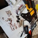 Sada komponentů pro elektrickou kytaru, zahrnující černý pickguard s instalovanými snímači a černé plastové knofíky. Na snímačích je vidět bílý nápis…