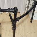 Černý kovový stojan, pravděpodobně pro klavír nebo synthesizer. Konstrukce tvoří dvě svislé nohy spojené v horní části vodorovnou popříčkou a dvěma b…