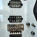 Detail korpusu elektrické kytary v bílé barvě. Nástroj je vybaven dvěma černými humbuckery s nápisem Seymour Duncan a chromovaným tremolo mostem s ná…
