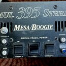 Černý kytarový zesilovač s nápisy SIMUL. 395 STEREO a Mesa/Boogie. Přední panel obsahuje ovládací knoflíky, přepínače a kontrolky s popisky jako TRAC…