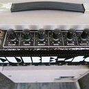 Kytarový kombo zesilovač značky Roland s nápisem CUBE-40. Horní ovládací panel obsahuje šest černých otočných knoflíků s popisy VOLUME, TREBLE, MIDDL…