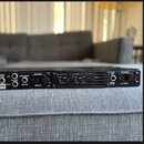 Zadní strana černého rackového zařízení s kovovým povrchem. Jsou zde viditelné nápisy: 120V 50-60Hz, LINE FUSE, I/O AMP TABLE, SPEAKER OUTPUT, EFX LO…