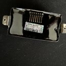 Černý elektrický snímač s kovovým povrchem a dvěma bočními uchyty. Na spodní straně je bílá nálepka s nápisy EMG-81TW, MADE IN USA, (21)4540392, 7057…
