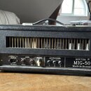 Černý kytarový zesilovač v koženkovém potahu s kovovými rohy a úchytem. Na předním panelu je nápis SOVTEK ® MIG-50 Made in Russia. Panel obsahuje ovl…