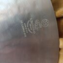 Detail kovového povrchu činely s vyrytými nápisy. Je zde vidět logo Zildjian, text K.ZILDJIAN & CO., GENUINE TURKISH CYMBALS a MADE IN USA. Dále je u…