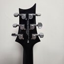 Zadní strana černé hlavy kytary s chromovanými ladičkami. Na ladičkách je vyryto logo PRS. Uprostřed hlavy je bílý nápis: Built by Cor-tek Musical In…