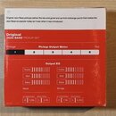 Fotografie krabice s nápisem Original JAZZ BASS® PICKUP SET. Na červeném pozadí je umístěn Pickup Output Meter s čísly 1 až 5 a grafy Output EQ pro N…