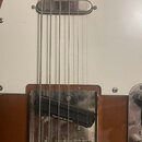Detail elektrické kytary s bílým pickguardem a hnědým trupem. Na kobylce je viditelný černý snímač s bílým nápisem Seymour Duncan. Povrch kovu kolem…
