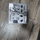 Kovový kytarový efekt s nápisem Bulldog Distortion a logem psa. Na horní straně jsou ovládací prvky s popisky GAIN 1, VOLUME 1, BASS, TREBLE, GAIN 2,…