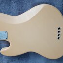 Zadní strana elektrické kytary v béžové barvě. Na kovovém krytu hned za krkovnicí je nápis Fender STRATOCASTER a symboly CE. V pravé části těla jsou…