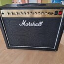 Kytarový kombo zesilovač značky Marshall, model DSL 40C. Má černý potah a bílý lem kolem mřížky reproduktoru. Na horním ovládacím panelu jsou umístěn…