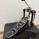 Fotografie zobrazuje basový pedál v černé a stříbrné barvě, umístěný na černém plastovém kufru. Na šlapce jsou viditelné nápisy „IRON COBRA“, „The le…