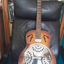 Akustická kytara typu resonator s hnědým gradientním lakem a chromovaným kovovým rezonátorem. Na hlavě hředu je bílý nápis Fender a na těle jsou dvě…