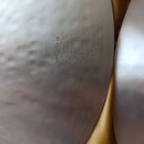 Detail stříbrného kovového činely s jemným žebrováním a klepaným povrchem. Na ploše je vyražen nápis „S/N 120598-024“ a logo ve tvaru hvězdy v kruhu.…