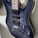 Modrá elektrická kytara s výraznou masivní strukturou dřeva na povrchu korpusu. Nástroj má tři humbuckery, jeden přepínač a dva ovládací knoflíky. Na…