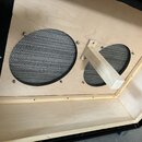 Interiér dřevěného boxu z překlijek s černým vnějším potahem. Uvnitř jsou dva kulaté reproduktory kryté černou kovovou mřížkou, připevněné šrouby. Me…