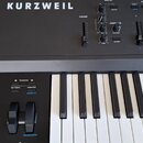Detailní pohled na černý klávesový nástroj se značkou KURZWEIL. Na ovládacím panelu jsou vidět posuvníky, otočné knoflíky a tlačítka s nápisy VOLUME,…
