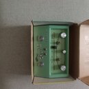 Světle zelený efektový pedál v kartonové krabici. Na předním panelu jsou nápisy Danelectro, Reel Echo a popisky ovládacích prvků: Sound On Sound, Ech…