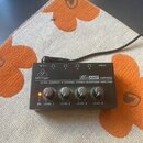 Černý kompaktní sluchátkový zesilovač s nápisy behringer a MicroAMP HP400. Na přední straně je text ULTRA-COMPACT 4-CHANNEL STEREO HEADPHONE AMPLIFIE…