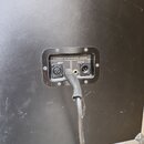Detail zadní strany černého přístroje s připojeným kabelem. Na panelu jsou nápisy A PRODUCT OF SOLTON MUSIC GERMANY, INPUT a OUTPUT. Jsou zde vidět d…