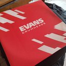 Červená čtvercová krabice s bílými grafickými prvky. Uprostřed je bílý nápis EVANS a pod ním menší text DRUMHEADS. V levém dolním rohu je malá bílá v…