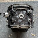 Fotografie znázorňuje buben s tmavě šedým, mramorovaným povrchem a chromovaným kováním. Uprostřed korpusu je圆形 štítek s nápisy „drums dw“ a „Collecto…