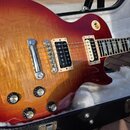 Elektrická kytara s tvarem single-cutaway a povrchovou úpravou v červeně-žlutém sunburstu s viditelnou strukturou dřeva. Nástroj má dva humbuckery v…