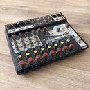 Míchací pult Soundcraft NOTEPAD-12FX s černým šasi a bílým horním panelem. Zařízení obsahuje řadu červených, žlutých a šedých otočných ovladačů a pos…