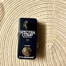 Tmavě modrý kytarový pedál s nápisem SPECTRA COMP a BASS COMPRESSOR. Ve spodní části je uveden text true bypass a logo tcelectronic. Pedál má jeden o…