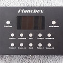 Černý obdélníkový přístroj s nápisem Pianobox. Uprostřed se nachází tmavý displej a kolem něj jsou rozmístěna ovládací tlačítka s bílými popisky: Pla…