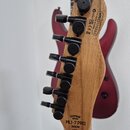 Záběr na zadní stranu dřevěné hlavy sedmistrunné kytary s černými ladičkami. Na dřevě je vyryto logo CHAPMAN GUITARS a model ML1-7 PRO MODERN. V horn…