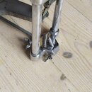 Detailní pohled na kovový mechanismus basového pedálu v chromovaném provedení. Součásti vykazují známky opotřebení a povrchové koroze. Na fotce nejso…