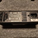 Zadní strana černého elektronického zařízení s ventilací a napájecím konektorem. Na povrchu je bílý nápis CAUTION, varovné symboly a text To prevent…