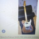 Elektrická kytara s přírodním dřevěným povrchem těla a bílým pickguardem. Nástroj má tvar typu Telecaster s kovovým mostkem a dvěma snímači. Na hlavě…