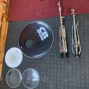 Na černém koberci leží černý bubnový korpus s bílým nápisem CB drums. Vedle něj jsou tři samostatné bubnové blány, z nichž jedna má nápis Pearl a dru…