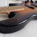 Elektrická basová kytara s korpusem v černé barvě s přechodem do hnědé a žluté (sunburst). Nástroj má světlý dřevěný hmatník bez pražců a čtyři strun…