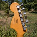 Zadní strana hlavy kytary z přírodního dřeva s šestma chromovanými ladičkami. Na dřevě je černý nápis „Designed and backed by Fender“, „Crafted in In…