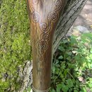Dřevěný didgeridoo s přirozeným hnědým povrchem a větvením v horní části. Nástroj je zdoben malovanými ornamenty tvořenými drobnými tečkami v červené…