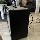 Černý kytarový kombozesilovač s povrchem z texturovaného vinylu. Na horní straně je umístena černá plastová rukojeť a v přední části jsou vidět ovlád…