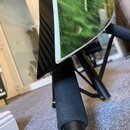 Detailní pohled na spodní část akustického nástroje s černým glossy povrchem a zeleným motivem na horní desce. Nástroj je umístěn na černém skládacím…