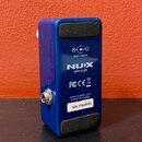 Modrý kytarový efekt pedál z kovového materiálu. Na spodní straně jsou dva černé gumovéstopy a nápisy: „9VDC 100mA“, logo „NUX MINI CORE“, „FC CE“ s…