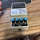 Bílý efekt pedál s nápisy Digital Delay a DD-7. Na horní části je černé logo BOSS. Zařízení má čtyři modře vybarvené ovládací knoflíky s popisky E.LE…