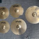 Sada pěti mosazných činelů značky Paiste. Na činelech jsou nápisy pAiste 20i1 a označení modelů: 12" crash, 16" crash, 20", 10" splash a 18" crash ri…