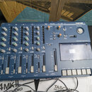 Modrý vícesledový záznamový zařízení s nápisem TASCAM a označením PORTASTUDIO 414mkII. Přístroj obsahuje čtyři kanály s posuvníky, řadu otočných knof…