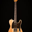 Elektrická kytara s přírodním dřevem těla a hředu. Na hlavě je viditelný nápis „Dunlop“. Kytara má tmavý hrací prkno a tmavě hnědý pickguard s bílými…