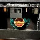 Zadní pohled na kytarový kombo zesilovač v černém truhle. Na horním ovládacím panelu je logo Peavey a nápis ValveKing VK 112. V interiéru je vidět re…