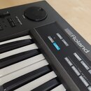 Černý klávesový nástroj s bílými a černými klávesami. Na horním panelu je bílé logo Roland a nápisy TUNE/FUNCTION, MIDI, KEY TRANSPOSE, DATA TRANSFER…