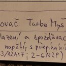 Fotografie zachycuje ručně psaný text na linkovaném papíře. Text v rámečku zní: „Kytarový zesilovač Turbo Myš – 5Watt“. Pod ním je dopisován text: „S…
